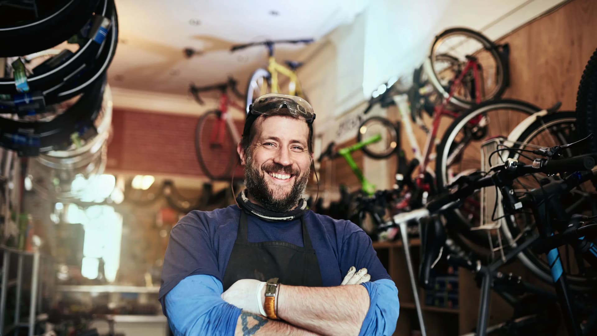 Mann mit verschränkten Armen lächelt in seinem Betrieb in die Kamera