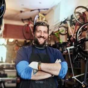 Mann mit verschränkten Armen lächelt in seinem Betrieb in die Kamera