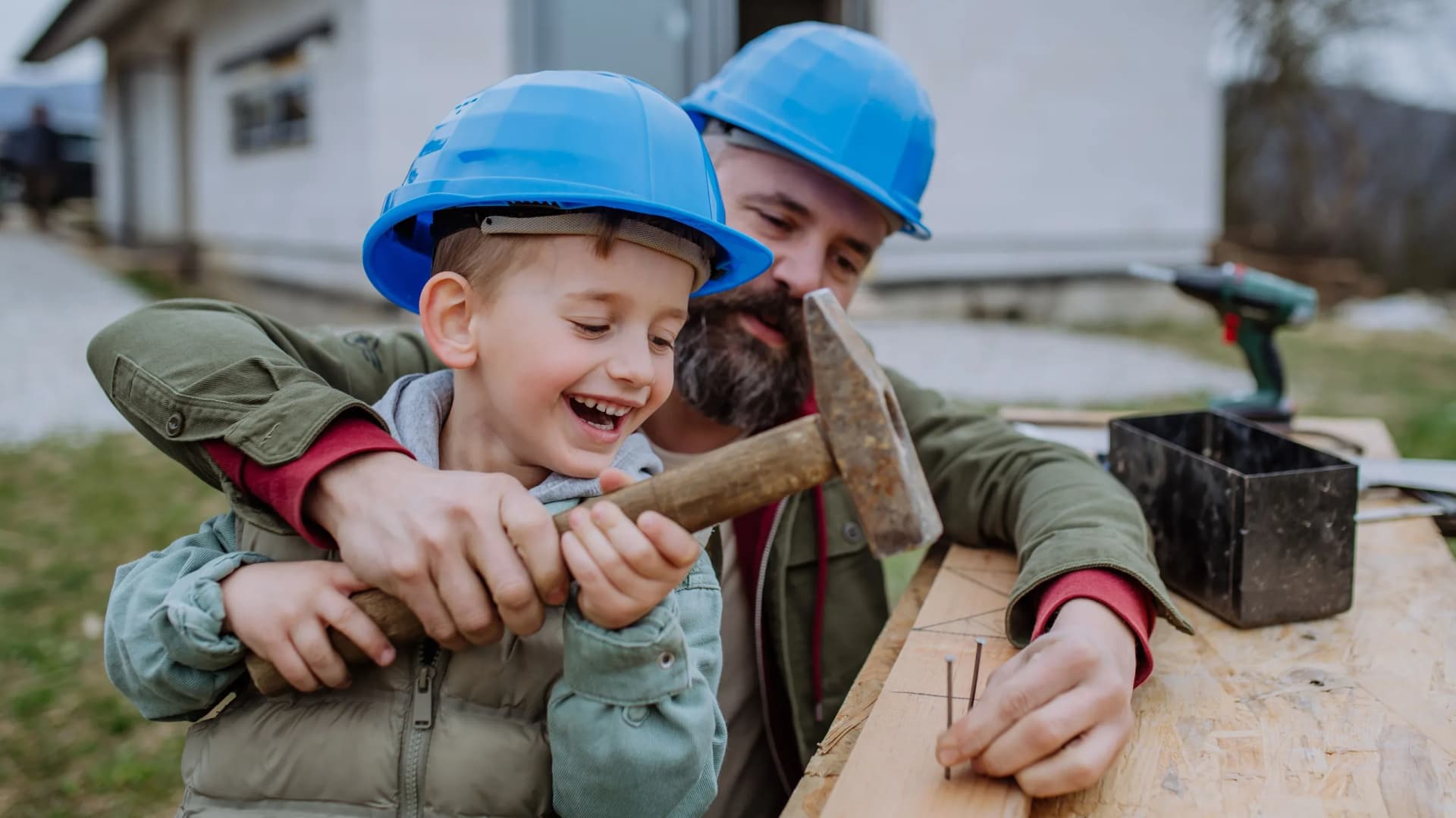Vater und kleiner Sohn hämmern auf Holzplatte als Symbolbild für Finanzieren mit Bank Burgenland: Flexible Finanzierungslösungen für Ihr Leben