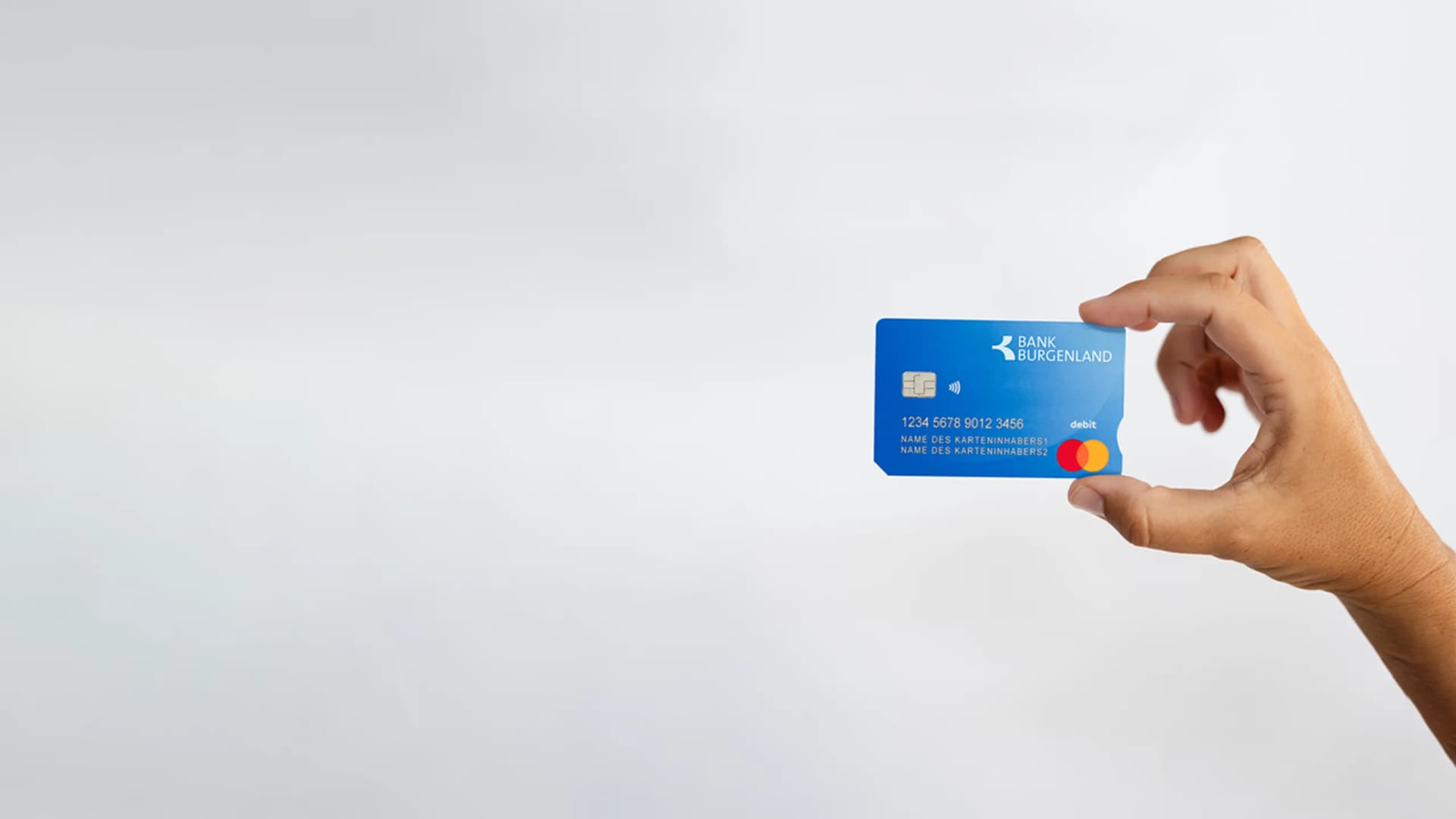 Eine Hand hält die Bankomatkarte der Bank Burgenland 