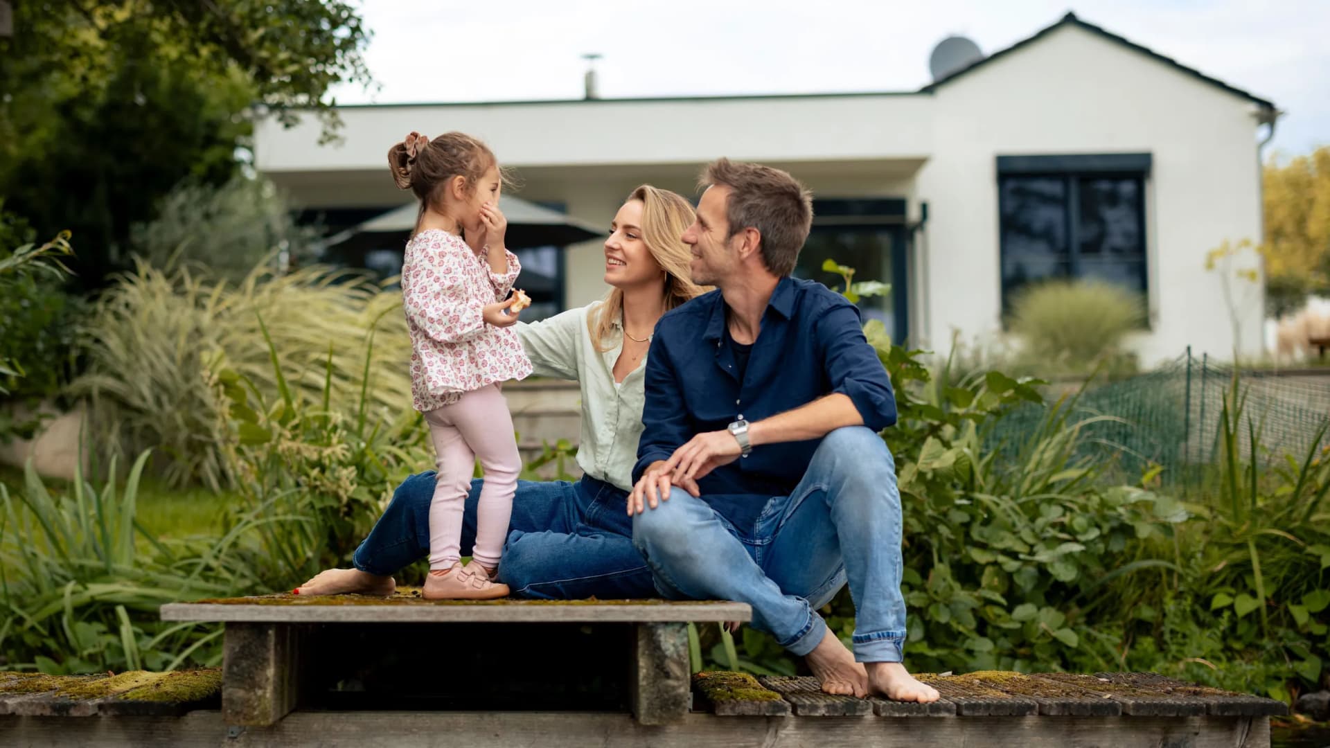Familie sitzt vor einem Haus